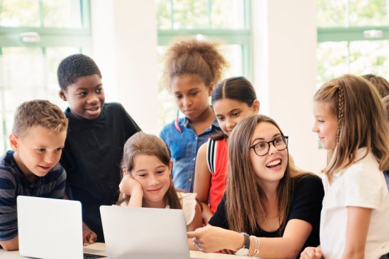 Kinderen die samen met hun juf naar een educatief pakket op de laptop kijken